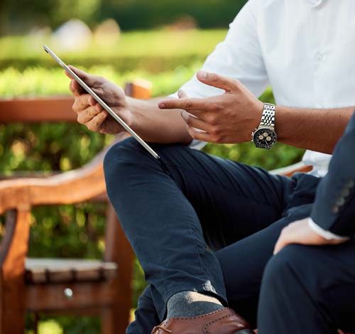 un homme montrant sa tablette tactile à un autre homme assis sur un banc